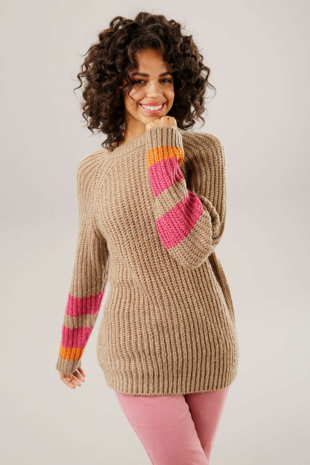 Вязаный свитер с разноцветными полосками на рукавах.